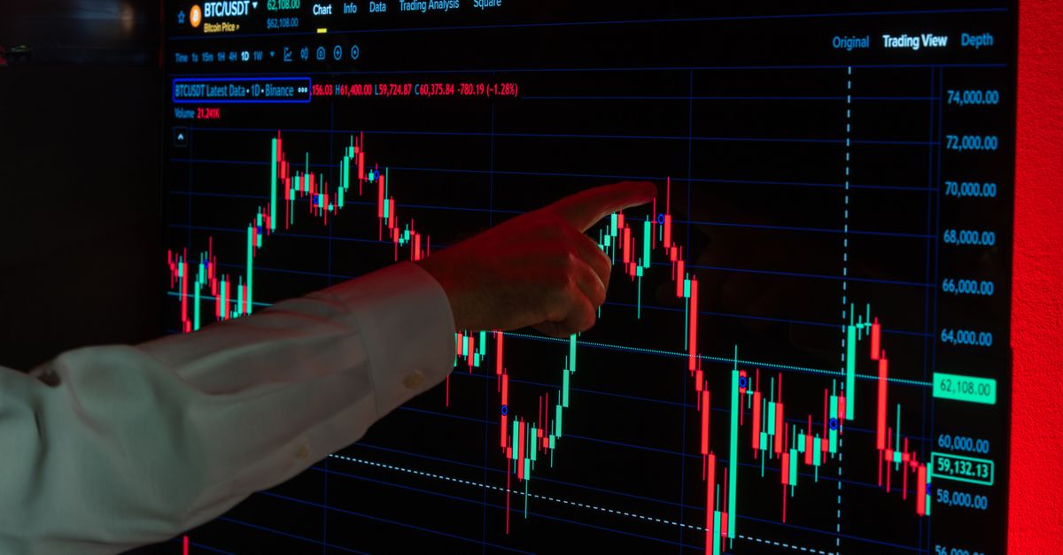 wall street trader pointing at green stock screen